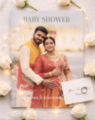 Baby shower invitation with a couple in traditional attire surrounded by flowers and lights.